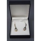 A yellow and white metal pair of drop earrings, set with emeralds, diamonds and a freshwater pearl.