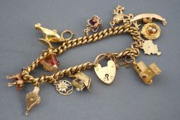 A yellow metal curb link bracelet with assorted charms. Padlock and safety chain.