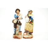 A pair of German slip cast bisque figures in traditional dress,
