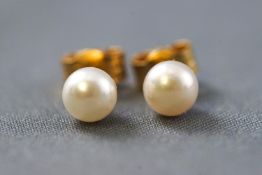 A yellow metal pair of single stone stud earrings