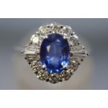 A white metal cluster ring set with a central blue sapphire