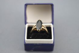 A yellow metal dress ring set with a marquise cut low commercial quality blackish sapphire