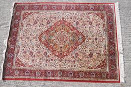A Middle Eastern rug of traditional design with a central lozenge motif on a cream ground,