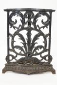 A cast iron corner stick stand, decorated with scrolling foliage,