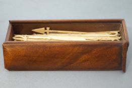A 19th century mahogany box with sliding cover containing a collection of bone Spillikins,