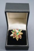 A yellow metal abstract design flower ring set with cabochon cut rubies and emeralds (one chipped)
