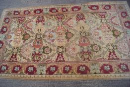 A large French style carpet with stylised flower heads and leaves on a beige ground