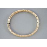 A yellow and white metal heavy twisted bangle. Push in clasp. Diameter: 65.0mm.