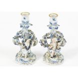 A pair of 19th century German porcelain candlesticks, decorated with figures in blue and white,