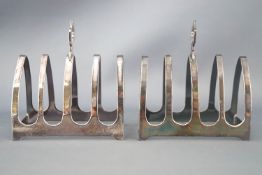 A pair of silver small form toast racks, of simple pointed Gothic arch form with a strap handle,