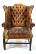 A leather wing back armchair with button back, seat and arms,