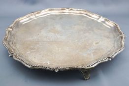 A silver salver with shaped bead edge raised on three anthemion style feet, Birmingham 1905,