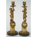 A pair of 19th century gilt metal and alabaster candlesticks in the form of putti