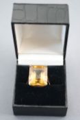 A yellow metal single stone ring. Set with a rectangular cut citrine quartz of approximately 24cts.