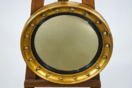 A convex mirror in round gilt frame with applied ball decoration and a tied ribbon motif border,