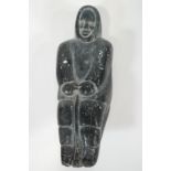 An 20th century Inuit soft stone carving of a figure, 20cm high,