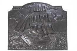 A cast iron fire back with a ship in full sail, painted black,