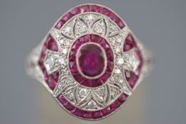 A white metal cluster ring set with an oval faceted cut ruby