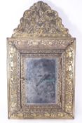 A 17th century Dutch style brass mirror frame with a grotesque cresting over concave sides,