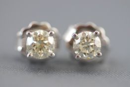 A white metal pair of single stone diamond stud earrings.