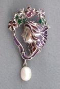 A white metal brooch depicting a female profile and flower design
