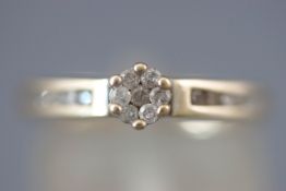 A yellow metal dress ring set with a cluster of seven round brilliant cut diamonds