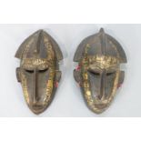 A pair of African brass mounted carved wood masks, of elongated form,