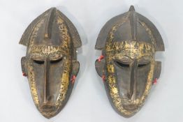 A pair of African brass mounted carved wood masks, of elongated form,