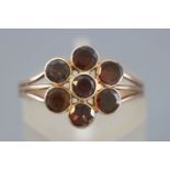 A rose metal flower cluster ring set with round faceted cut garnets.