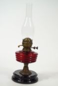 A Victorian oil lamp with ruby red glass reservoir,