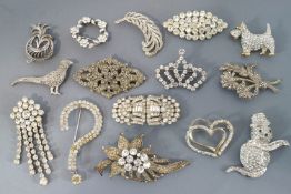 A collection of fifteen base metal paste stone set costume brooches of variable designs.