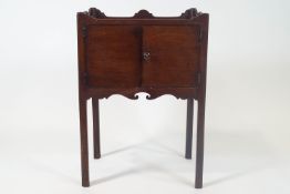 A 19th century mahogany commode with tray top above two doors on square legs,