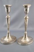 A pair of silver oval candlesticks with bead edged sconces with fluted decoration on similar stems