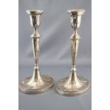 A pair of silver oval candlesticks with bead edged sconces with fluted decoration on similar stems