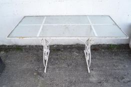 A wrought iron metal garden table with a ripple glass top,