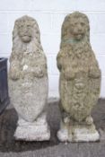 A pair of reconstituted stone lions, seen sejant gardant,