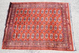 A Middle Eastern rug of traditional design with a rust coloured group,