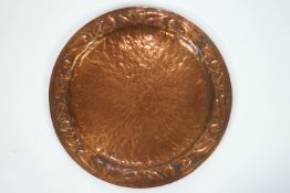 A copper Arts and Crafts style charger, with embossed leaf and berry rim,