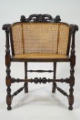 A tub chair with caned back and seat, with turned legs linked by turned stretchers,