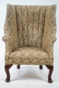 A wing back armchair on mahogany cabriole legs and pad feet