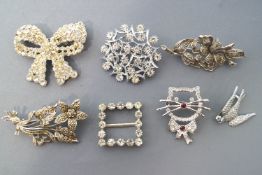 A collection of fifteen white base metal paste stone set brooches of variable designs.