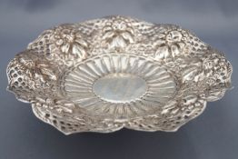 A marked Islamic white metal dish repousse decorated with flowers and fruit in a pierced border