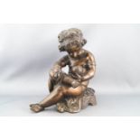 A bronze figure of a seated, draped Putto