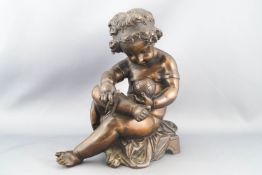 A bronze figure of a seated, draped Putto
