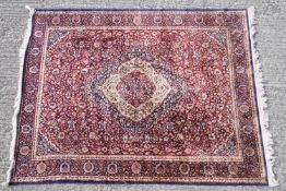 A Middle Eastern rug of traditional design with a central lozenge motif on a claret ground,