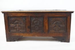 A 17th century style oak coffer with triple carved panel front,