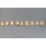 A yellow metal panel bracelet having nine oval links each set with an oval carved shell cameo,