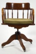 An early 20th century oak office chair with Captains style back,