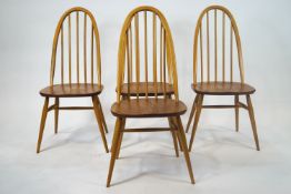 A set of four marked Ercol dining chairs with bentwood beech stick backs and stretchered legs,