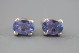 A white metal pair of single stone stud earrings.